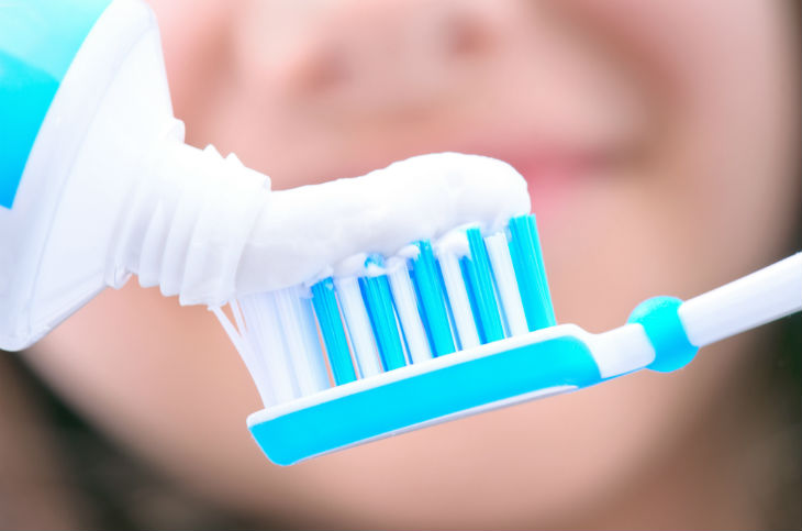 Persona echando pasta de dientes a un cepillo de dientes